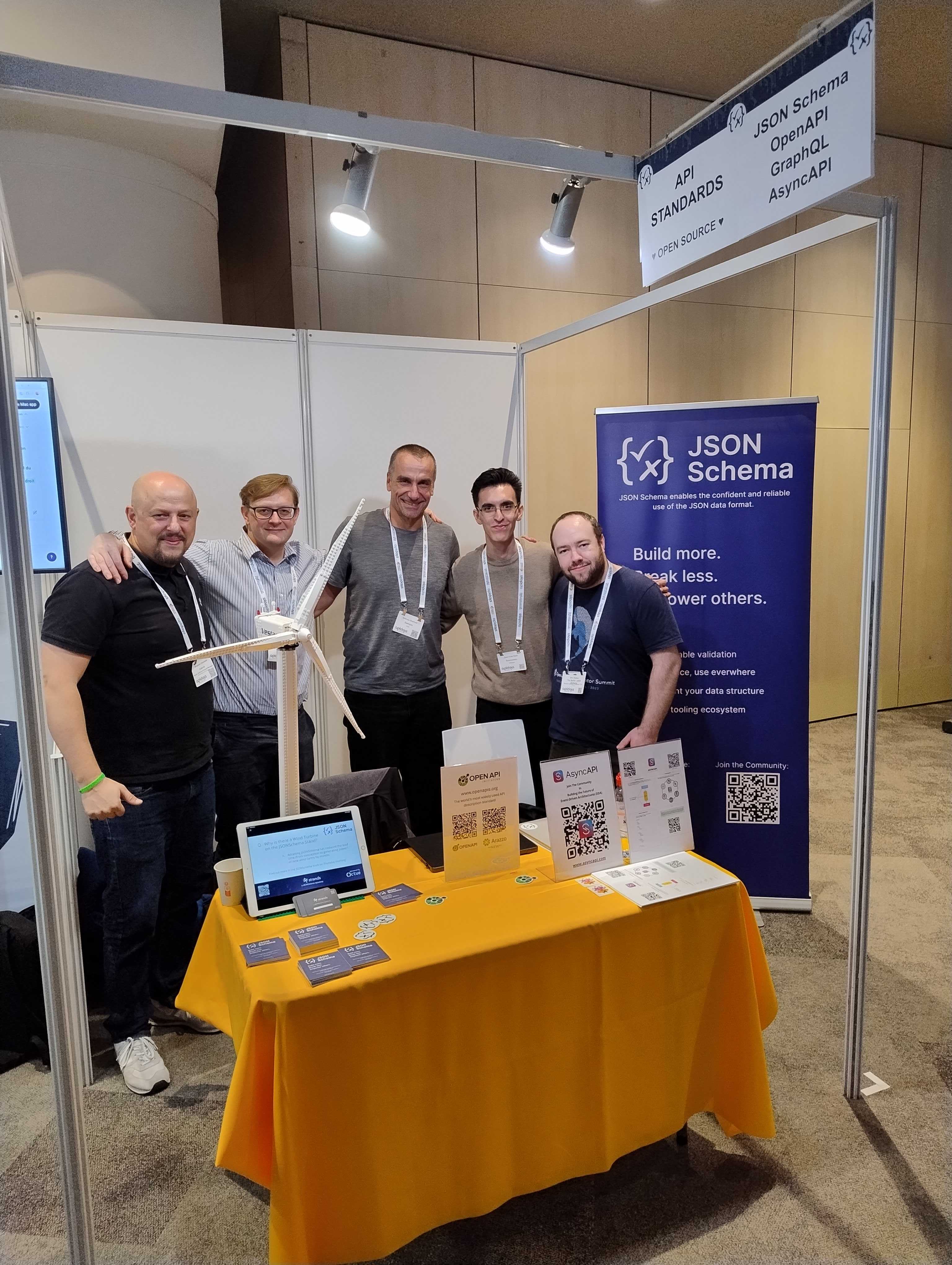 Five people standing at a booth labeled 'Standards'. They are smiling and looking at the camera. From left to right, their names are Benjamin Granados, Thomas Clark, Andreas Eberhart, Juan Cruz Viotti, and Ben Hutton.